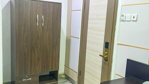 A room with a wardrobe, a door, a desk, and a blue mat. - Rosepearl Hotel And Suites (Lagos)
