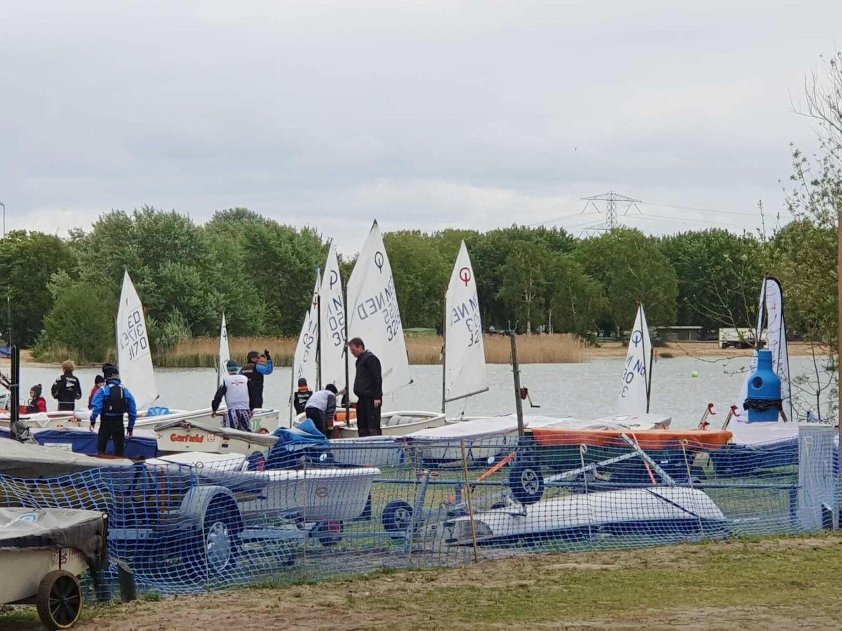 Ein Segelboot mit weißem Segel, auf dem 'ED 3170' steht, liegt an einem Gewässer festgemacht.