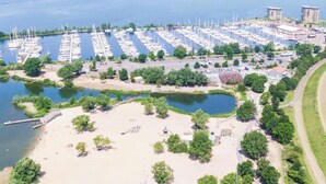 Un puerto deportivo con numerosas embarcaciones amarradas, una zona de playa arenosa y algo de vegetación.