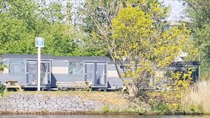 Casas móviles en fila junto a un lago, con un cartel que indica la zona de embarque de barcos.