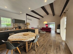 A modern kitchen with a dining area, wooden flooring, and a red sofa in the living room. - Villa with pool (Saint-Jean-de-Cuculles)