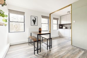 A modern kitchen with white cabinets, a wooden floor, and a window with a view. - Boutique 1BR Pimlico | 1 Min to Tube | Zone 1 (Greater London)