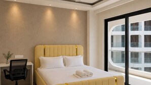 Ein modernes Hotelzimmer mit einem großen Bett, einem Schreibtisch, einem Stuhl und Blick auf die Stadt.