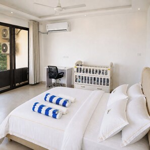 Une chambre d’hôtel équipée d’un lit, d’un bureau, d’une chaise, d’un berceau et d’un appareil de climatisation.