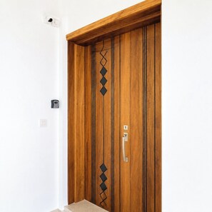 Une porte en bois ornée d’un motif géométrique, avec une poignée et un interrupteur sur le mur.