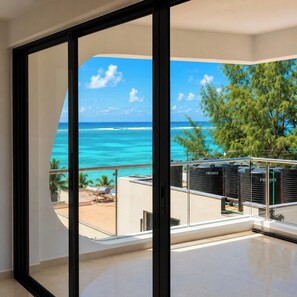 Un balcon avec vue sur l’océan et les palmiers.