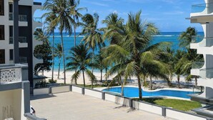 Ein modernes Hotel mit Pool, Palmen und Blick auf den Strand.