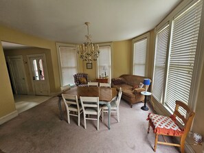 A dining area with a table and chairs, a sofa, and a chandelier.