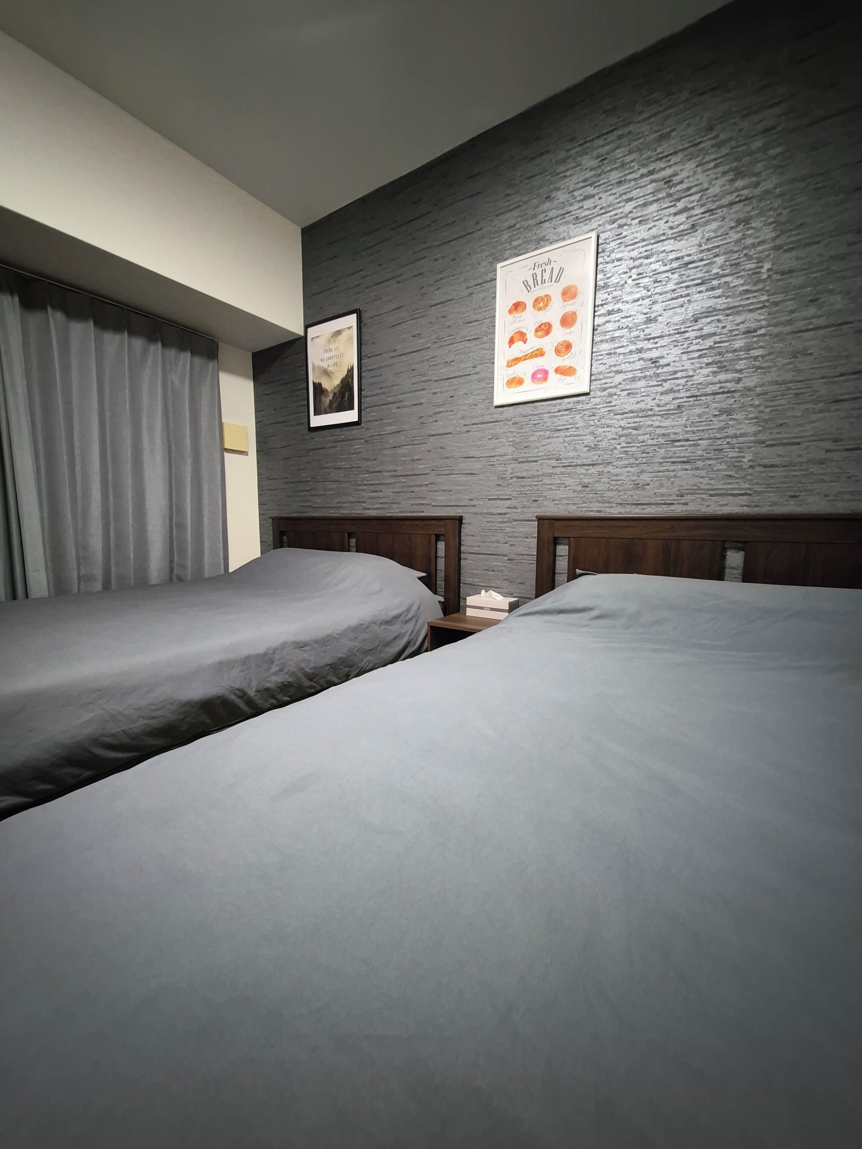 Ein Schlafzimmer mit zwei Einzelbetten, einem Nachttisch, einem gerahmten Bild und einem Wandposter.