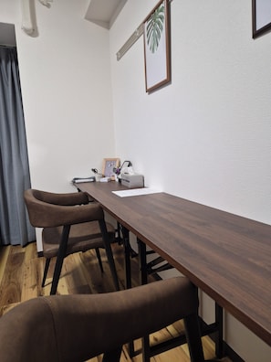 A conference room with a long wooden table, two brown chairs, a framed plant, and a whiteboard. - HK House (Osaka)