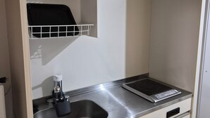 Eine kleine Küchenzeile mit Spüle aus Edelstahl, einer Kaffeemaschine und einer eingebauten Mikrowelle.