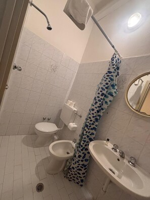A bathroom with a toilet, bidet, sink, shower, and a towel rack. - Baia Serena (Bellaria-Igea Marina)