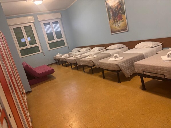 A room with multiple beds, a massage chair, and a poster on the wall.