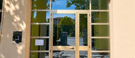 L’entrée d’un immeuble, avec une enseigne indiquant « Baia Serena » et un symbole représentant le soleil.