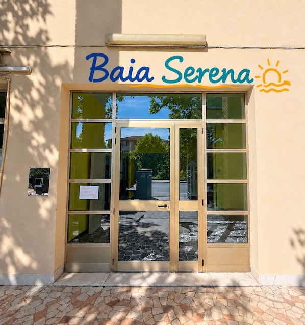 A building entrance with a sign reading 'Baia Serena' and a sun symbol. - Baia Serena (Bellaria-Igea Marina)
