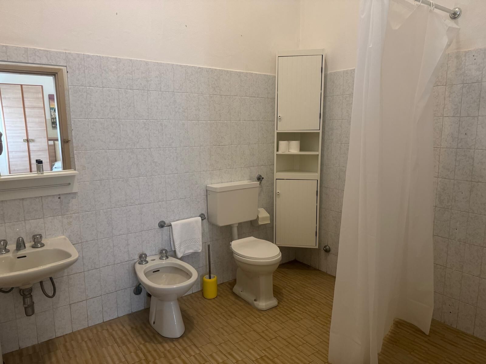 Un baño con lavamanos, bidé, inodoro y un armario.