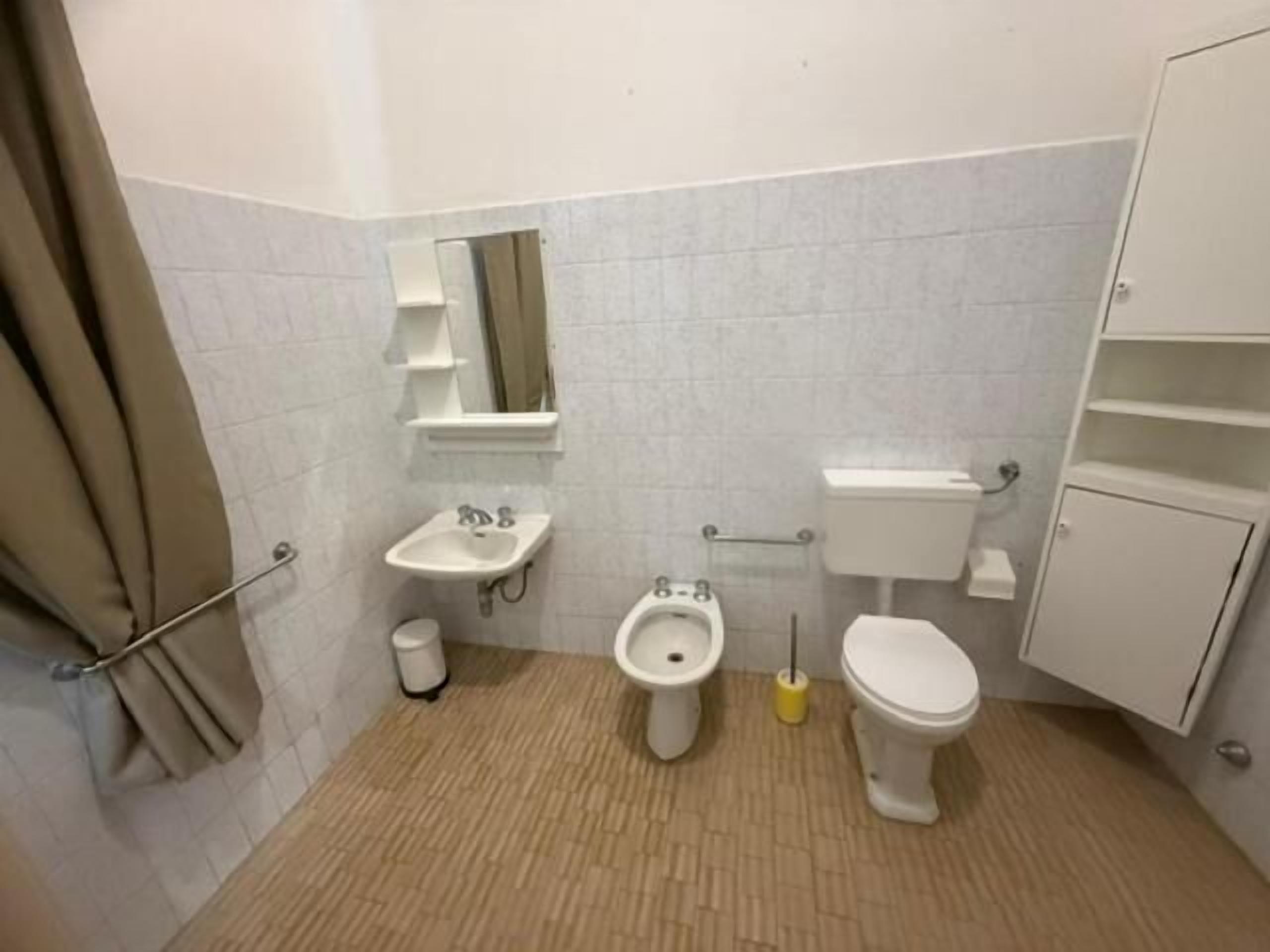 A small bathroom with a toilet, bidet, sink, and a mirror.