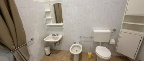 A small bathroom with a toilet, bidet, sink, and a mirror.