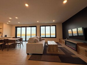 Un soggiorno moderno con un divano grande, un'area pranzo e una TV a parete.