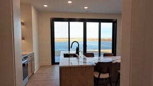 A modern kitchen with a large island, a dining area with a view, and a spacious room with wooden flooring. - Private Waterfront Lake House Near Omaha (Valley)