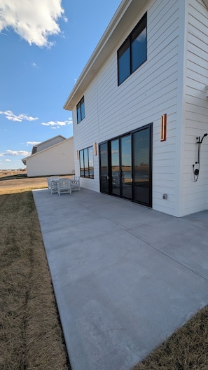 Ein modernes, zweistöckiges Haus mit Terrasse, großen Fenstern und Blick auf die Landschaft.