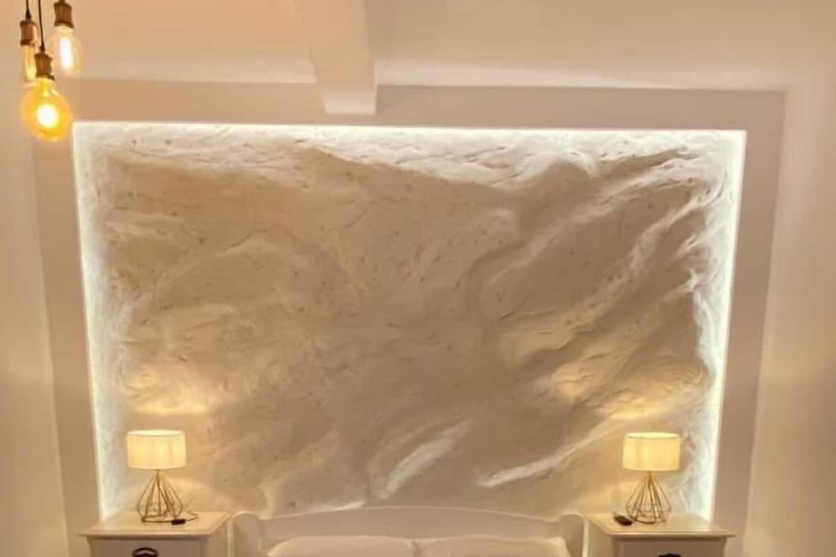 Un dormitorio moderno con una cama grande, dos mesitas de noche con lámparas, una pared con textura y una alfombra.
