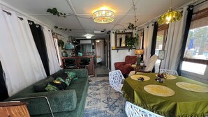 Um quarto aconchegante com um sofá verde, uma mesa de jantar com jogos americanos amarelos e um tapete estampado.