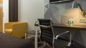 A hotel room with a bed, a desk, a chair, a TV, and a lamp. - 2 Person Holiday Park Home in Brauschweig (Braunschweig)