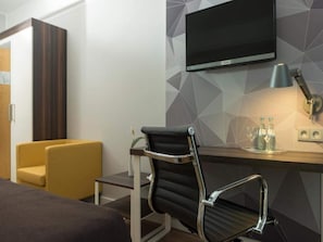 A hotel room with a bed, a desk, a chair, a TV, and a lamp. - 2 Person Holiday Park Home in Brauschweig (Braunschweig)