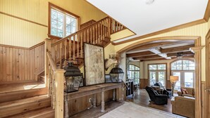 A spacious interior with a wooden staircase, a stone fireplace, and a dining area. - 6 bed 5 bath cottage on Lake Rosseau (Nipissing South (Utterson))
