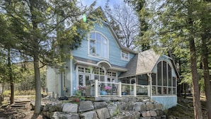A house with a large porch, stone steps, and a view of the surrounding forest. - 6 bed 5 bath cottage on Lake Rosseau (Nipissing South (Utterson))