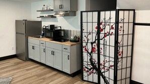 A modern kitchen with a refrigerator, microwave, and wooden countertop.