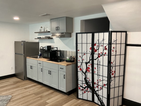 A modern kitchen with a refrigerator, microwave, and wooden countertop.