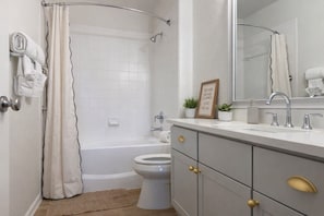 Ein Badezimmer mit einer Badewanne, Toilette und einem Waschtisch mit Spiegel.