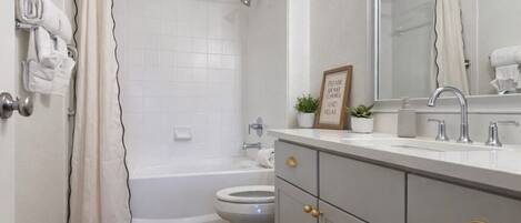 Une salle de bain moderne équipée d’une baignoire, de toilettes et d’un meuble-lavabo avec un miroir.