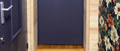 A dark blue door with a silver handle, a wooden door frame, and a welcome mat at the entrance.