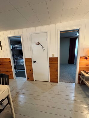 Ein Zimmer mit Etagenbett, Schreibtisch, Stuhl und einer Tür mit einer Dekoration.