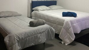 A hotel room with two beds, a ceiling fan, and an air conditioning unit.