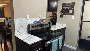 A kitchen with a stove, microwave, and cabinets. There is a coffee bar sign on the wall.