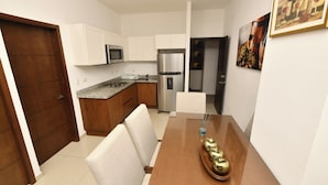 A compact kitchen with a microwave, refrigerator, and dining area with a table and chairs. - Bonito departamento con vista al mar  (Mazatlán)