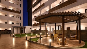A multi-story hotel with a rooftop terrace, outdoor seating area, and a wooden pergola. - Bonito departamento con vista al mar  (Mazatlán)