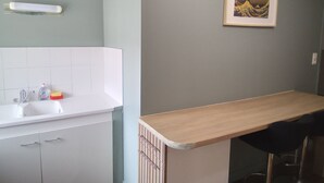A kitchen with a white countertop, a wooden bar counter, and a framed picture on the wall. - Champagne character apartment (Essoyes)