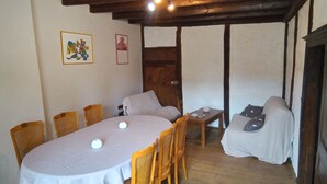 A dining area with a table, chairs, a sofa, and a wooden ceiling. - Champagne character apartment (Essoyes)