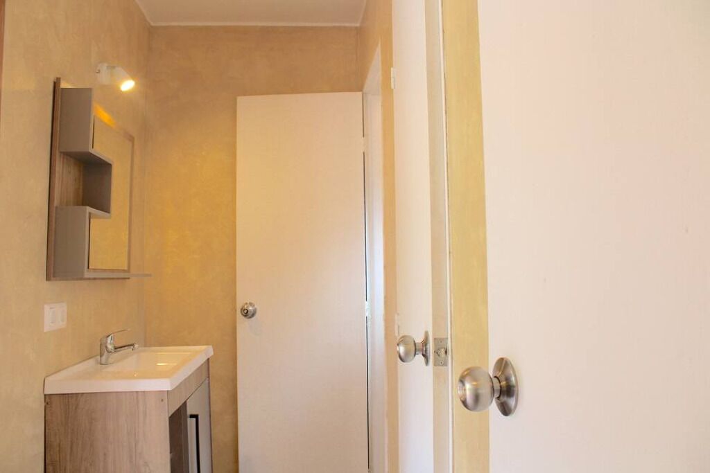 A bathroom with a sink, mirror, and a door.