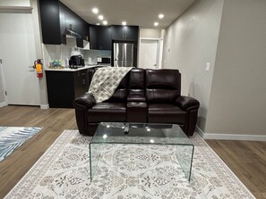 Ein Wohnzimmer mit einem Ledersofa, einem Glastisch und einem gemusterten Teppich.