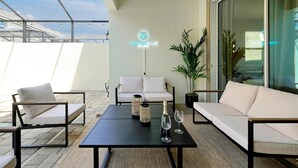 Een buitenruimte met een tafel, twee banken en een neonbord met de tekst 'TIFFANY'S VILLAS SOLARA'.