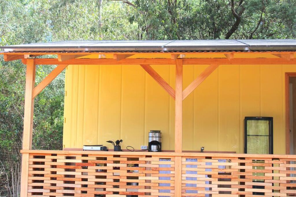 A yellow building with a wooden porch and a metal roof.