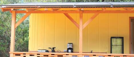 A yellow building with a wooden porch and a metal roof.