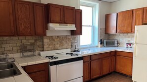 Una cucina con pensili in legno, un piano cottura bianco, una lavastoviglie, un forno a microonde e un frigorifero.