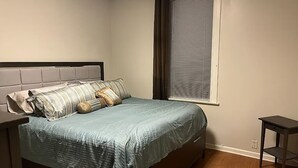 Una camera da letto con un letto, una finestra con persiane, un comodino e un tavolino.